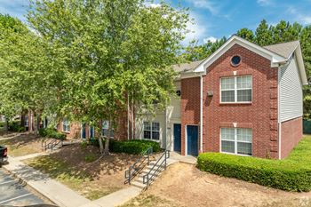 our apartments offer a spacious courtyard with trees and a brick building at Greens at Stonecreek, Lithonia, 30038
